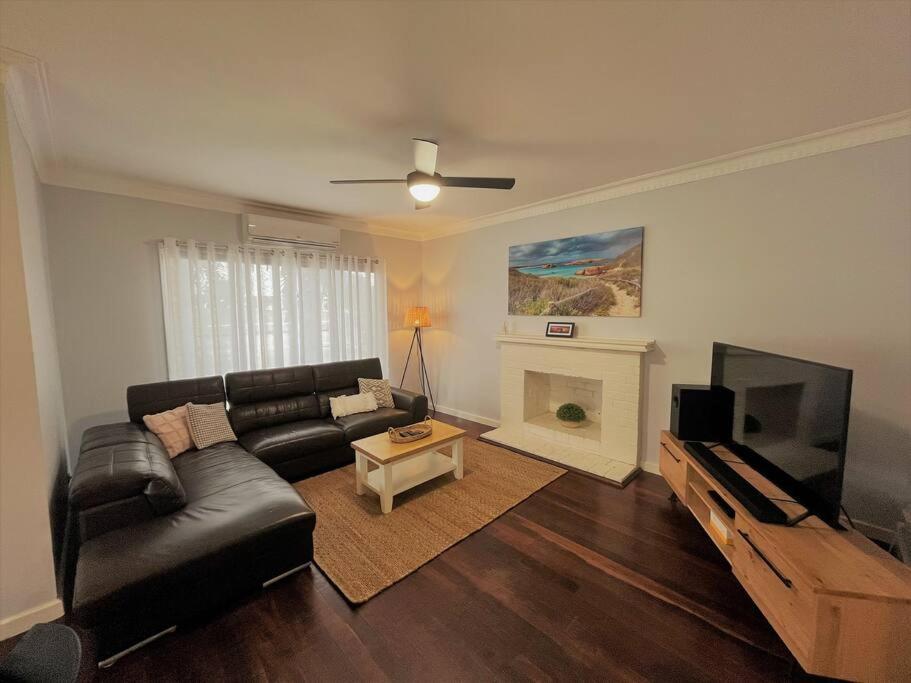 a living room with a black leather couch and a television at Dempster House in Esperance