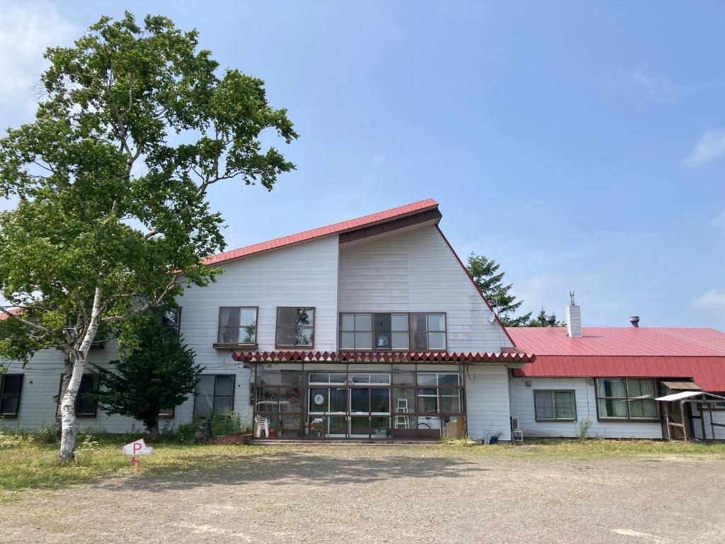 duży biały budynek z czerwonym dachem w obiekcie Mashuko Youth Hostel w mieście Teshikaga