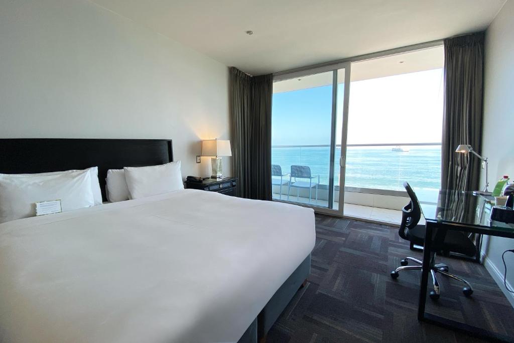 a hotel room with a large bed and a large window at Wyndham Garden Antofagasta Pettra in Antofagasta