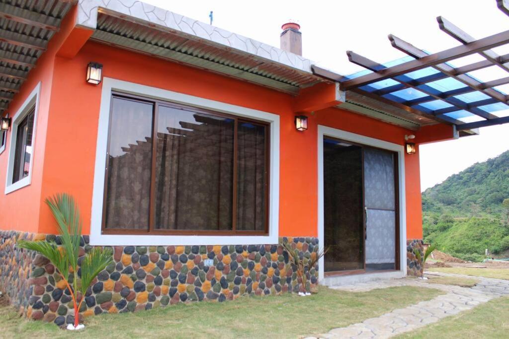 Casa Cabaña En San Carlos Panamá في سان كارلوس: منزل برتقالي بجدار صخري أمامه