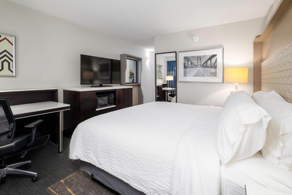 a hotel room with a large white bed and a desk at Holiday Inn Weirton-Steubenville Area in Weirton