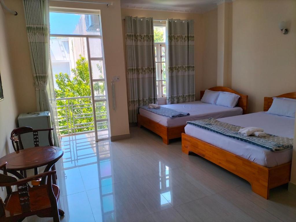 a hotel room with two beds and a balcony at Nhà Nghỉ KHÁNH NGỌC in Vung Tau