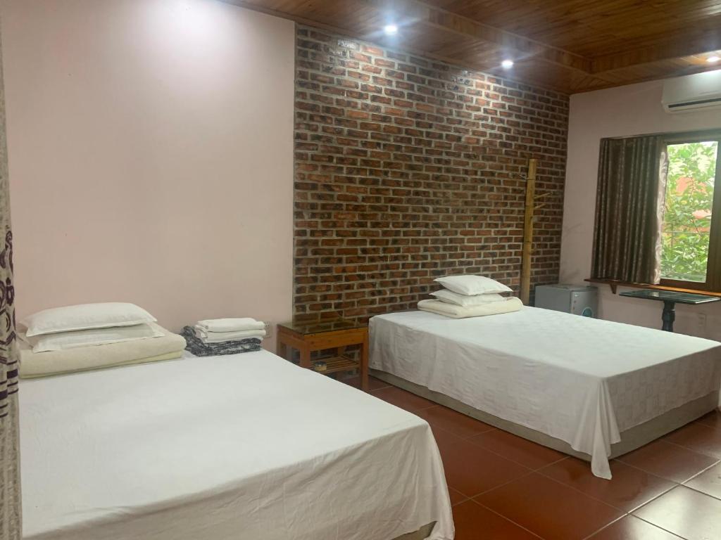 two beds in a room with a brick wall at Nhà hàng-Khách sạn Hồ Núi Đính in Ninh Binh