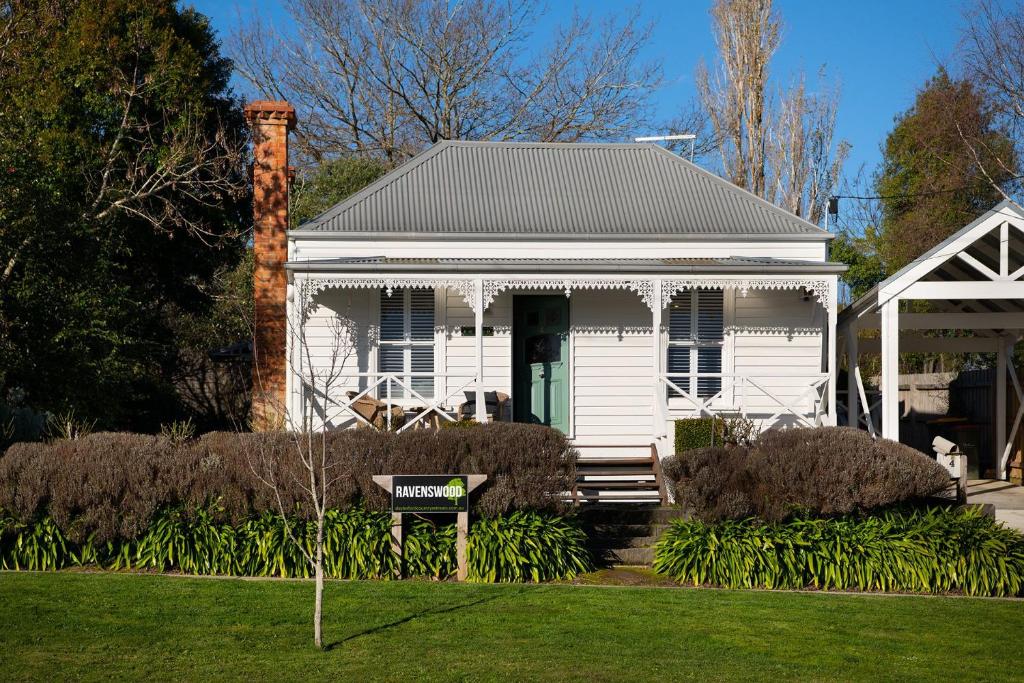 una casa blanca con un cartel delante en Ravenswood, en Daylesford