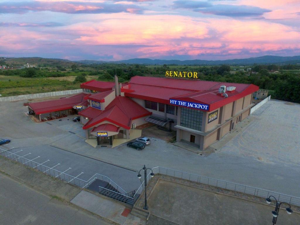 un restaurante con techo rojo y aparcamiento en Casino Motel Senator, en Gevgelija