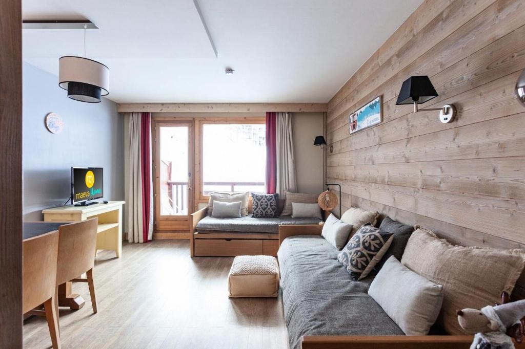 a living room with a couch and a wooden wall at Résidence Le Christiana - maeva Home - Appartement 2 Pièces 5 Personnes - Sélection MAE-3642 in Saint-Bon-Tarentaise