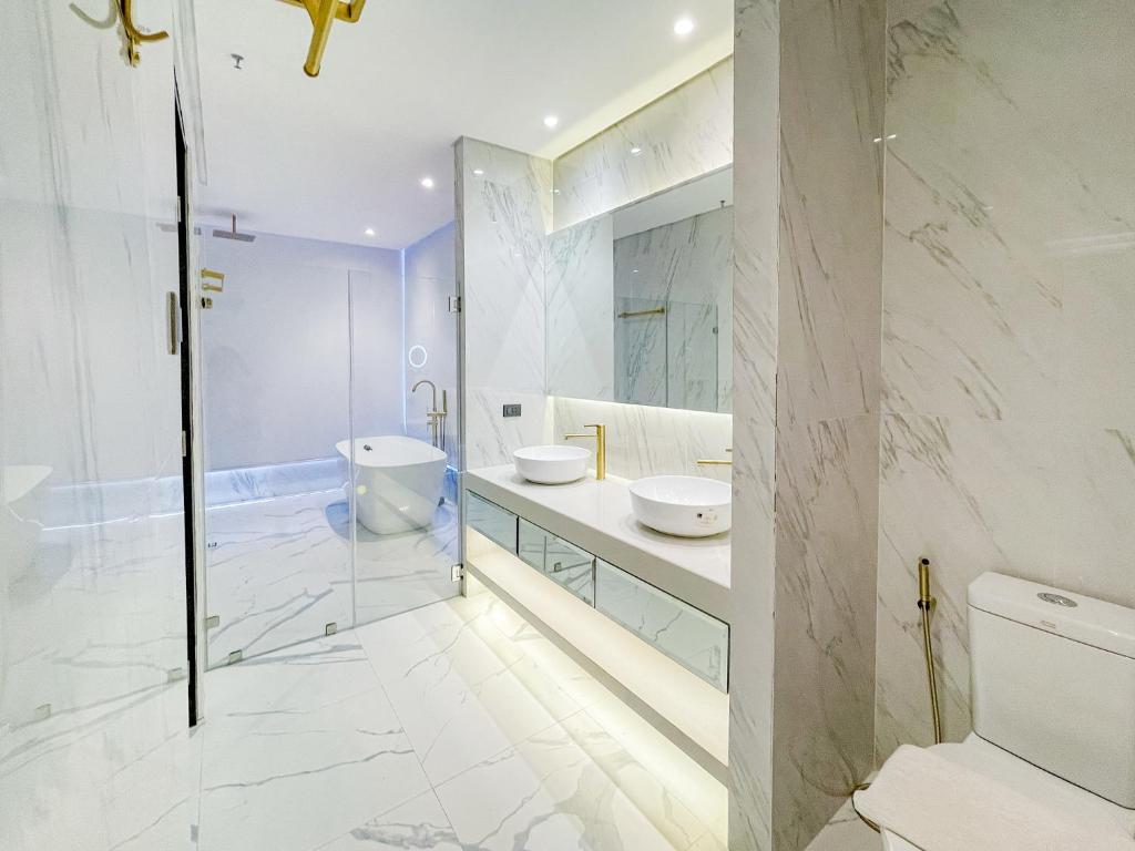 y baño con 2 lavabos, aseo y ducha. en Ironwood Hotel, en Tacloban