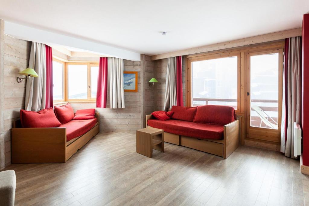 uma sala de estar com dois sofás vermelhos e janelas em Résidence Le Christiana - maeva Home - Appartement 2 Pièces 7 Personnes - S 12 em Saint-Bon-Tarentaise