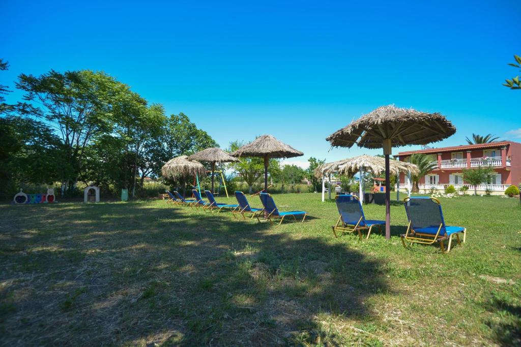 een rij stoelen en paraplu's in een veld bij Giannis and Fridas Garden in Sidari