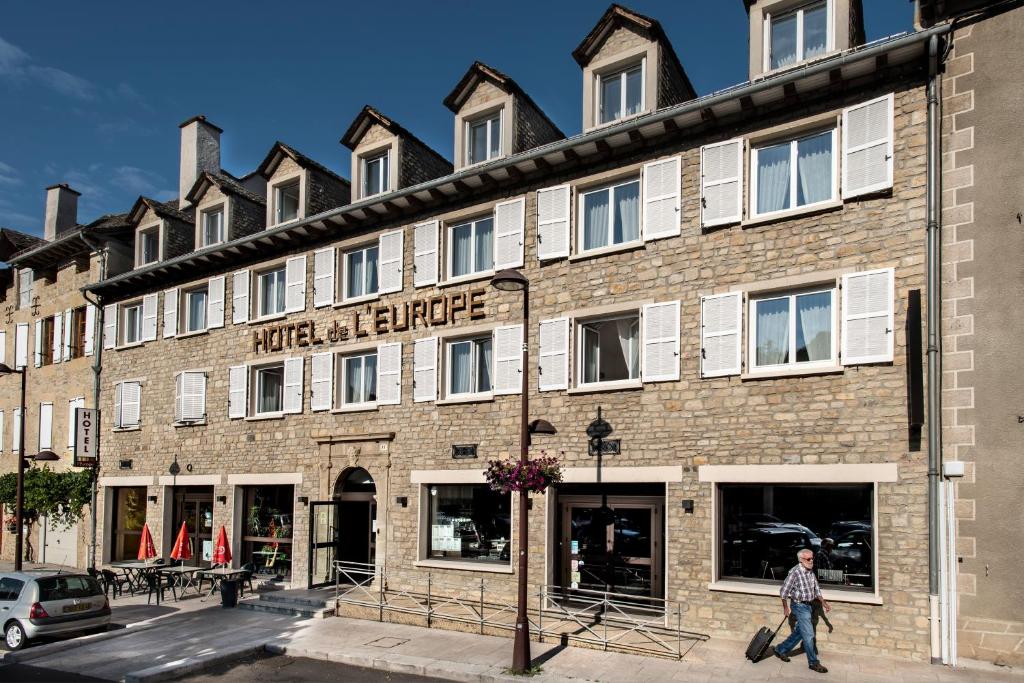 un homme marchant devant un bâtiment dans l'établissement Logis Hôtel Restaurant L'Europe, à Marvejols