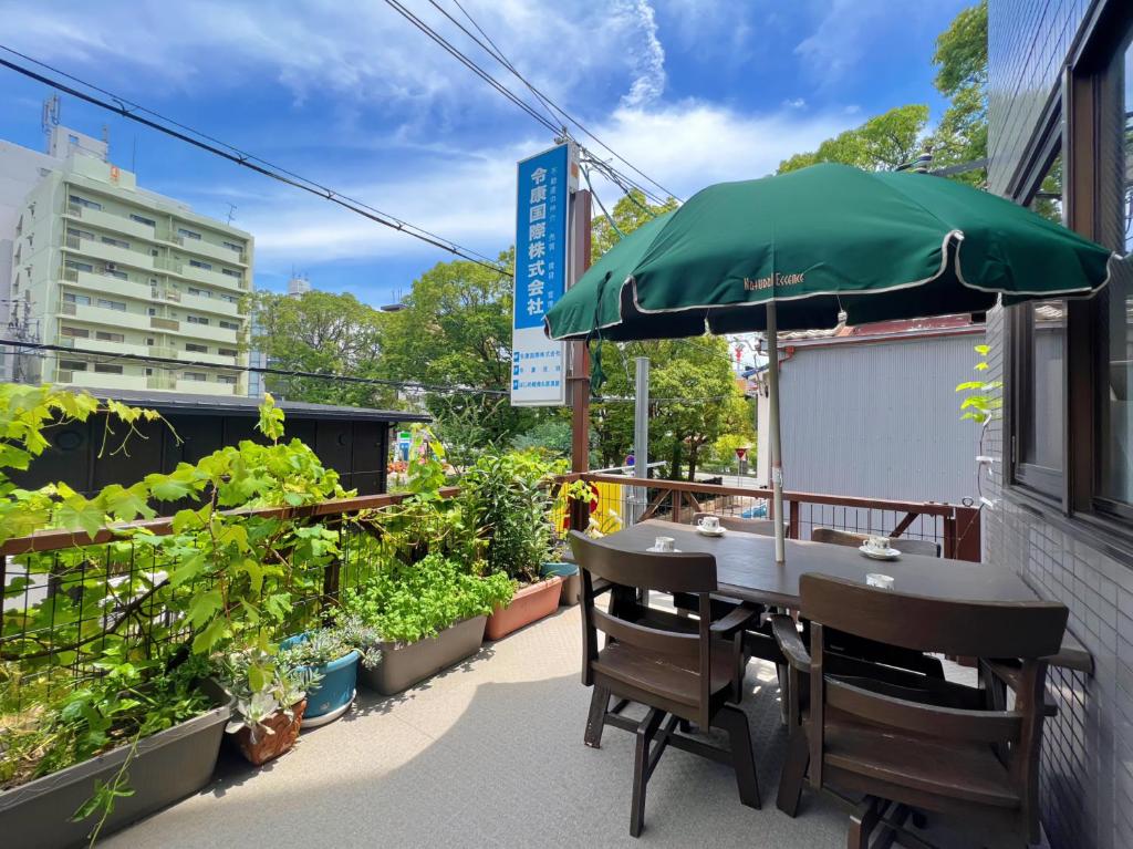 uma mesa com um guarda-chuva verde e algumas plantas em 千間川ー天王寺 em Osaka