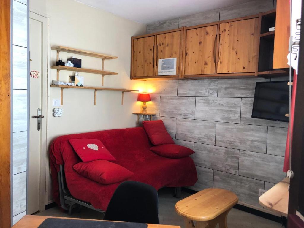 ein Wohnzimmer mit einem roten Sofa und einem TV in der Unterkunft Résidence quartier Hauts-Forts - Maeva Particuliers - Studio 4 Personnes Confort - Le Pas du Lac 124223 in Morzine