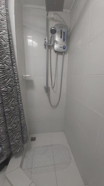 La salle de bains blanche est pourvue d'une douche. dans l'établissement Cozy condo for rent, à Davao