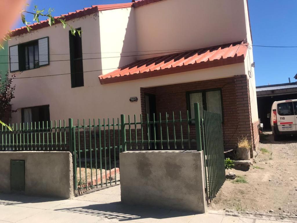 una casa con una valla verde delante de ella en Family Hostel en Perito Moreno