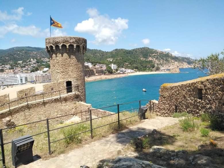 a castle next to a body of water with a flag at San Jordi Tossa de Mar in Tossa de Mar