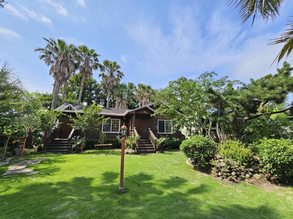 a house with palm trees in the yard at Valley Village in Seogwipo