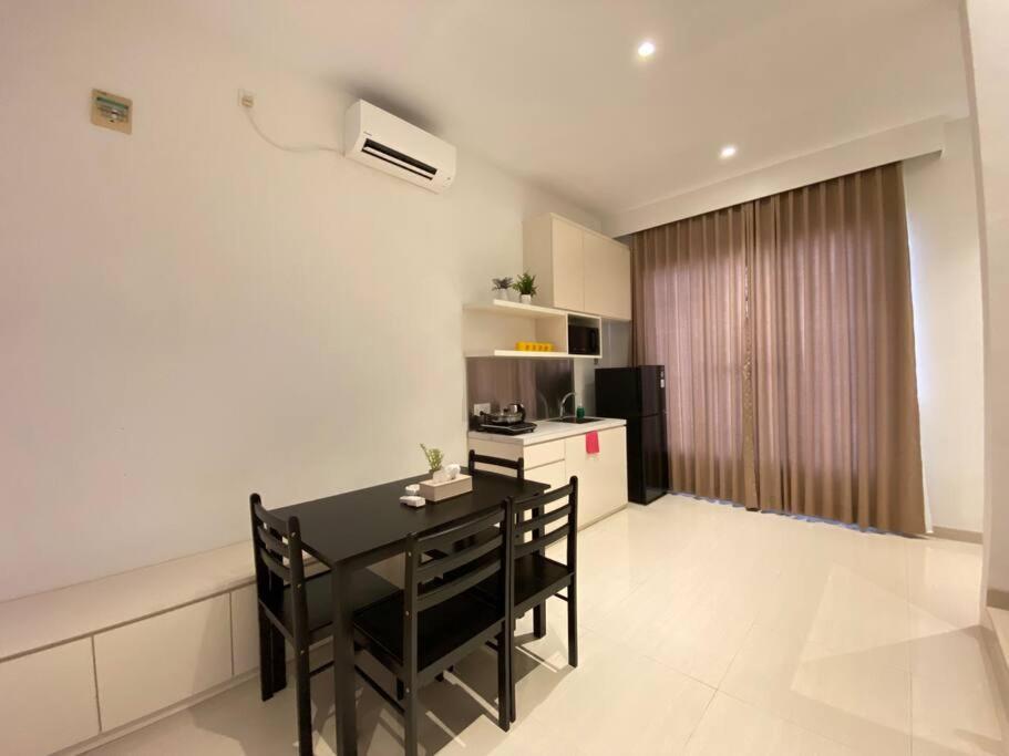 uma sala de jantar com uma mesa preta e uma cozinha em Monde Residence I no 6 Batam Centre em Sengkuang