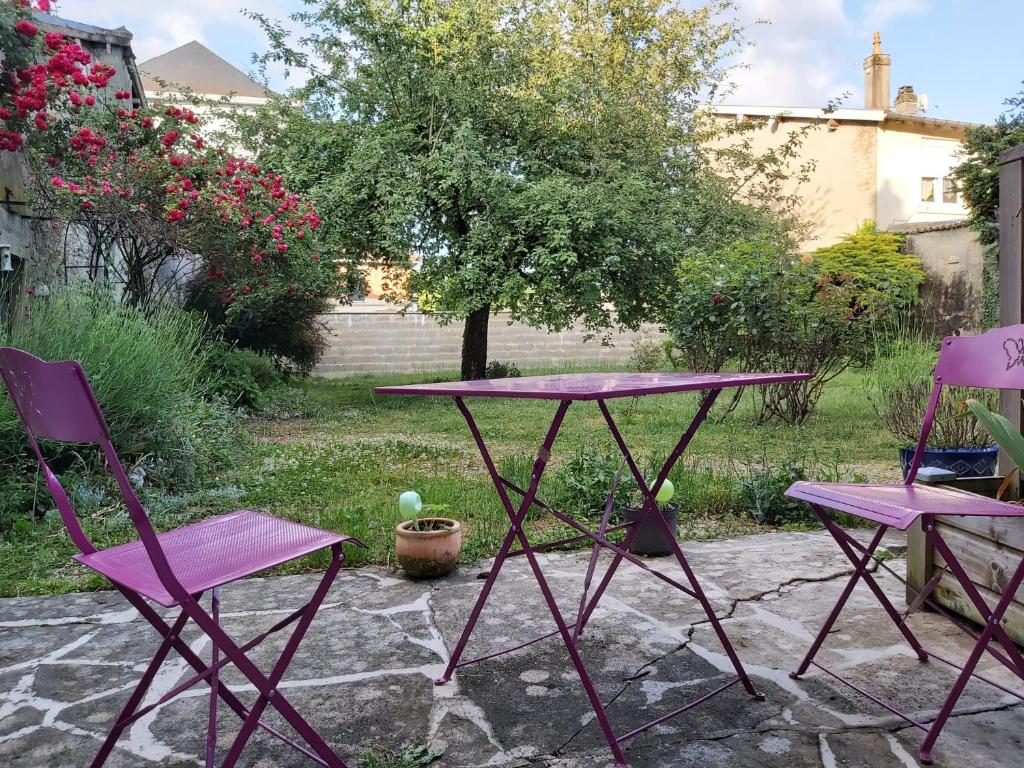 dos sillas púrpuras y una mesa en un patio en Studio RDC avec terrasse, en Ligny-en-Barrois