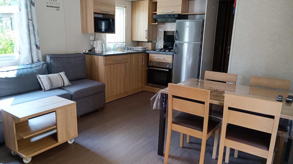 sala de estar con sofá y cocina en Mobil home 3 ch domaine de kerlann pont aven wifi inclu en Pont-Aven