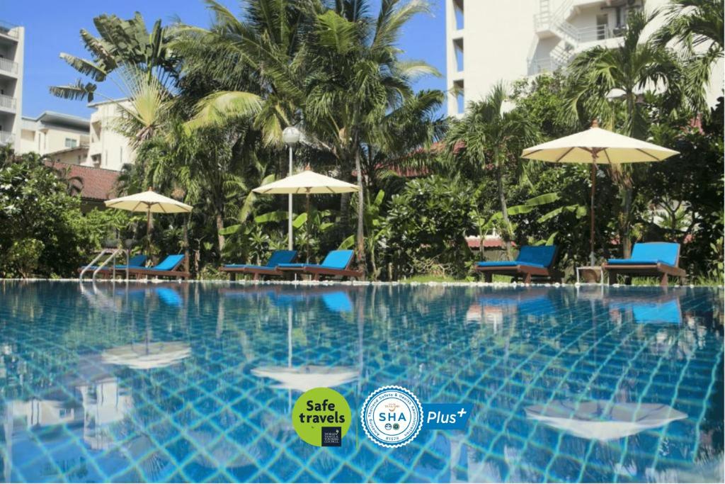 uma piscina num resort com cadeiras e guarda-sóis em Patong Palace Hotel - SHA Extra Plus em Patong Beach