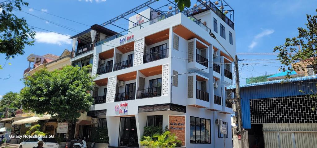 a white building with orange trim on a street at Park Inn Boutique and Hostel in Kampot
