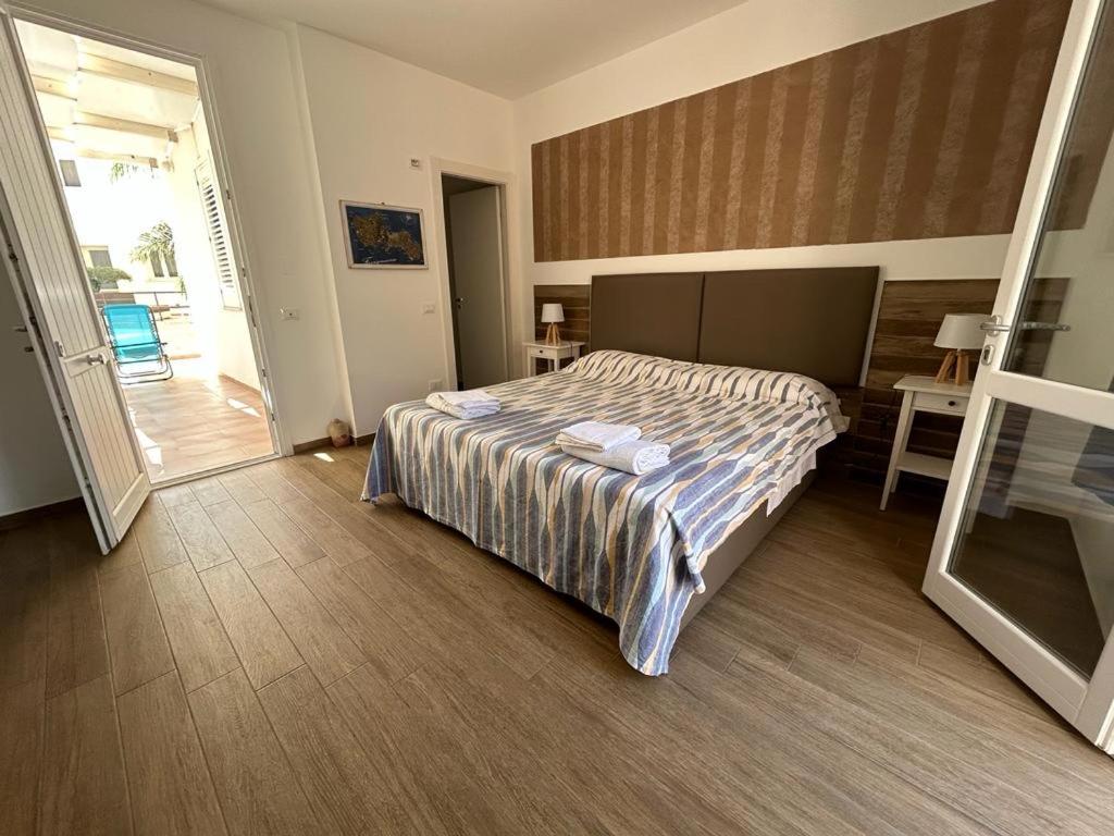 - une chambre avec un lit et une porte donnant sur une terrasse dans l'établissement Monolocale Mulino, à Favignana