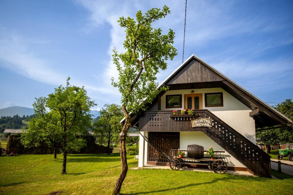 a house with a staircase and a tree at Apartment Vidmar in Bohinj