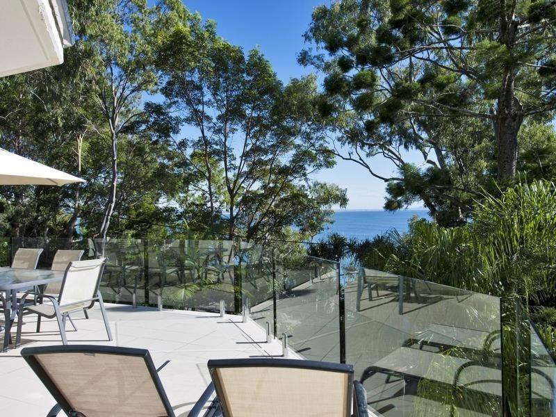 een patio met stoelen en een tafel en de oceaan bij Kareka Apartment 2, Little Cove in Noosa Heads