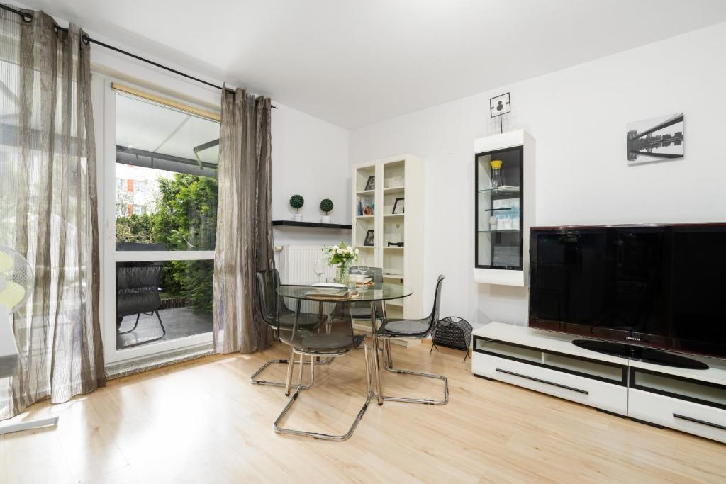 uma sala de estar com uma mesa e uma grande televisão em Cozy Apartment Karpia 17 with Terrace & PARKING in Poznań by Renters em Poznań