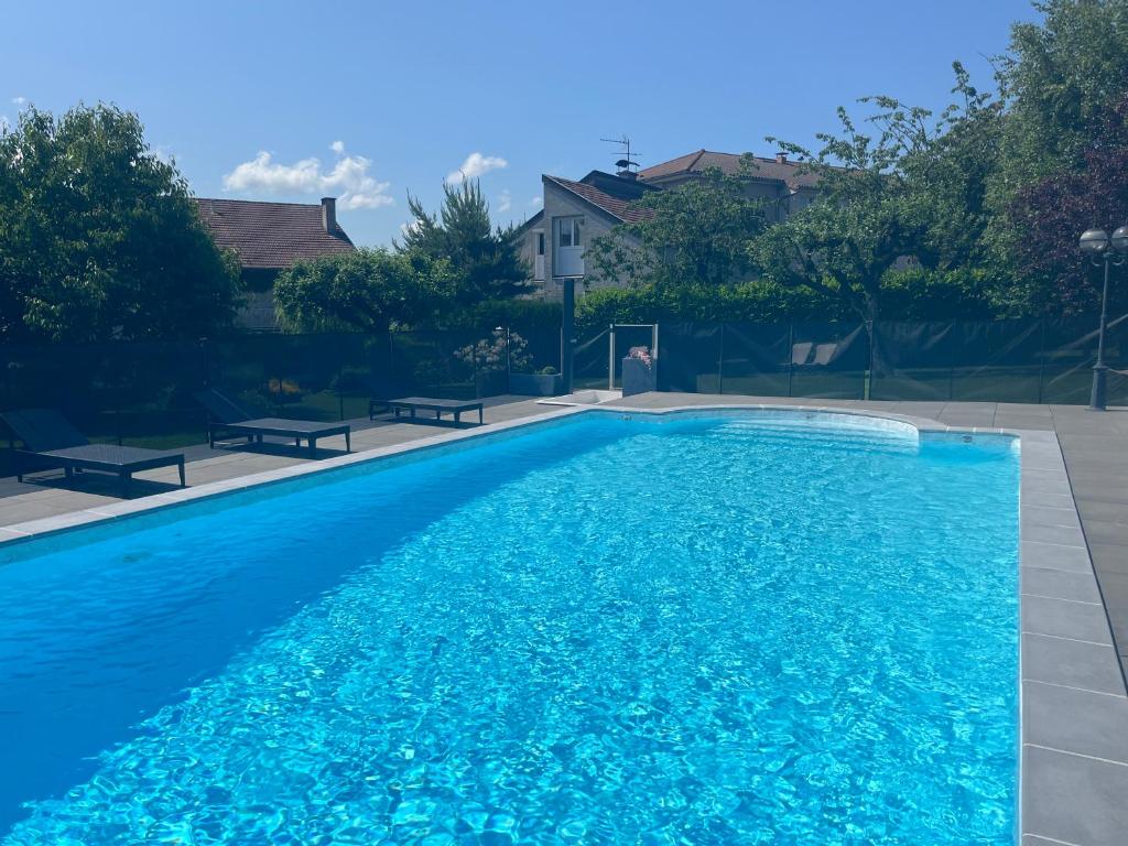 uma grande piscina azul com dois bancos à volta em Logis La Thomasse em Aurillac