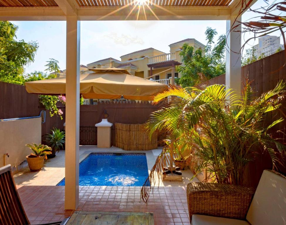 a patio with a swimming pool and an umbrella at Dar 66 Plunge Pool Resort Townhouses in Ras al Khaimah