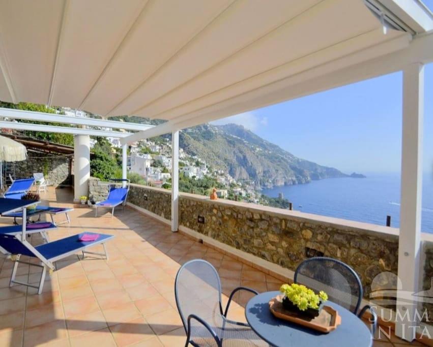 uma varanda com mesas e cadeiras e vista para o oceano em Villino Blu em Praiano