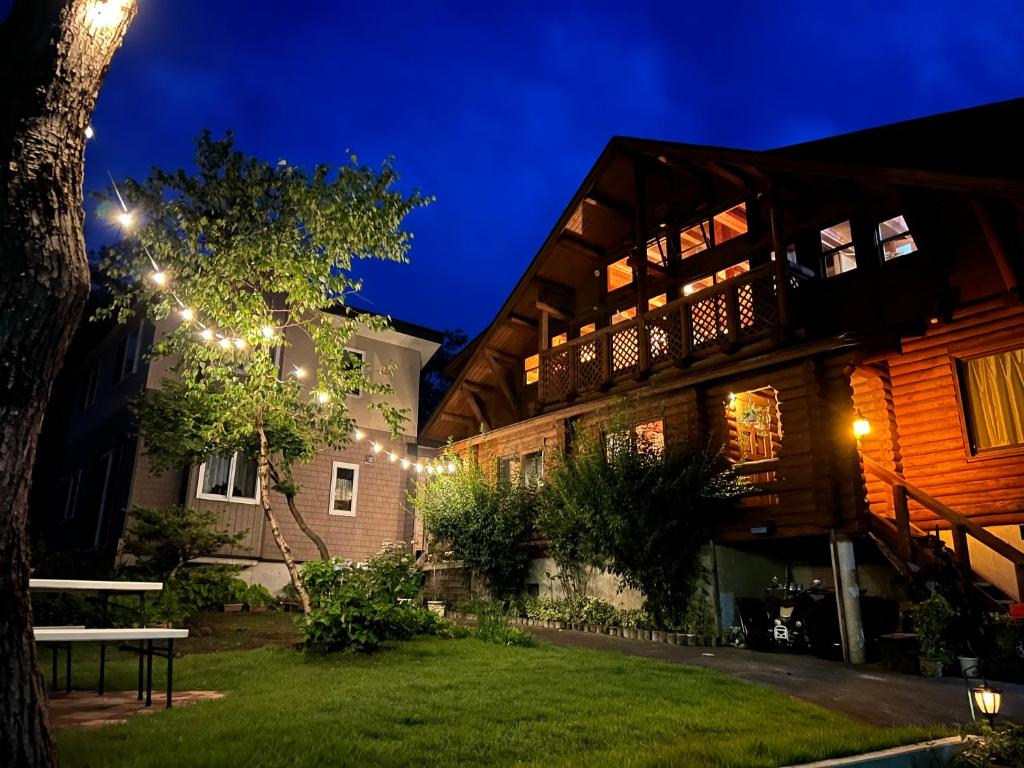 una casa con luces en el patio por la noche en Log Pension Tomsoya en Myoko