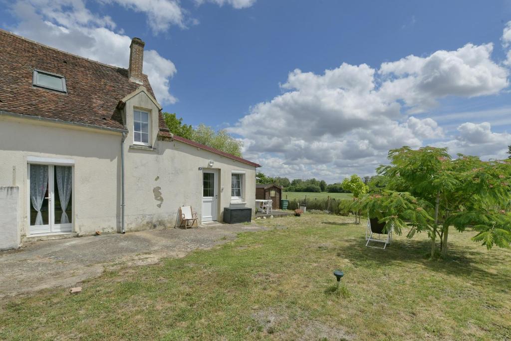 a white house with a yard with chairs and trees at Cozy Perche - Maison avec jardin in Cour-Maugis-sur-Huisne