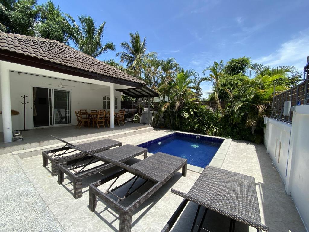 a patio with two picnic tables and a swimming pool at Orchid Villa in Ko Tao