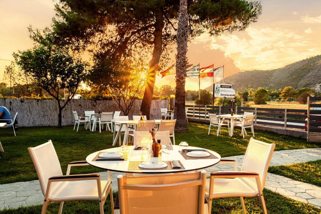 une table et des chaises avec le coucher du soleil en arrière-plan dans l'établissement Kalogria Summer Retreats - Seimeio Strofilia, Sunny Vibes, à Kalogria