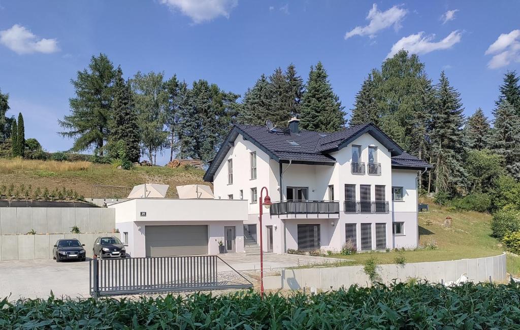 a white house with a car parked in a parking lot at Ferienapartment 21 in Kurort Gohrisch