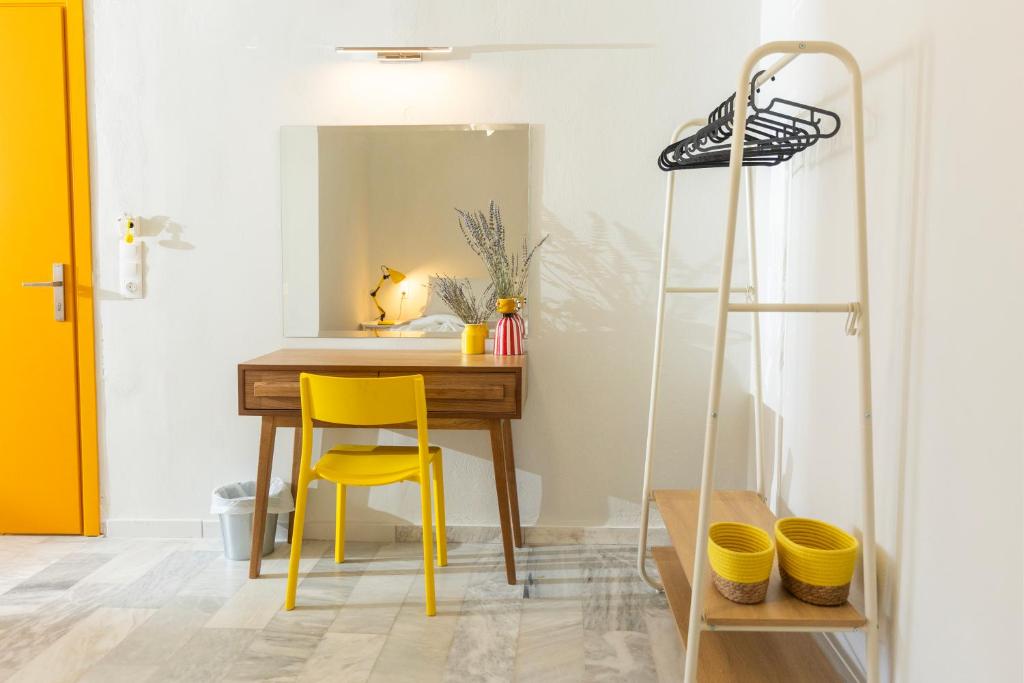una scrivania con sedia gialla in una stanza con specchio di Mondrian Guest House a Città di Skiathos