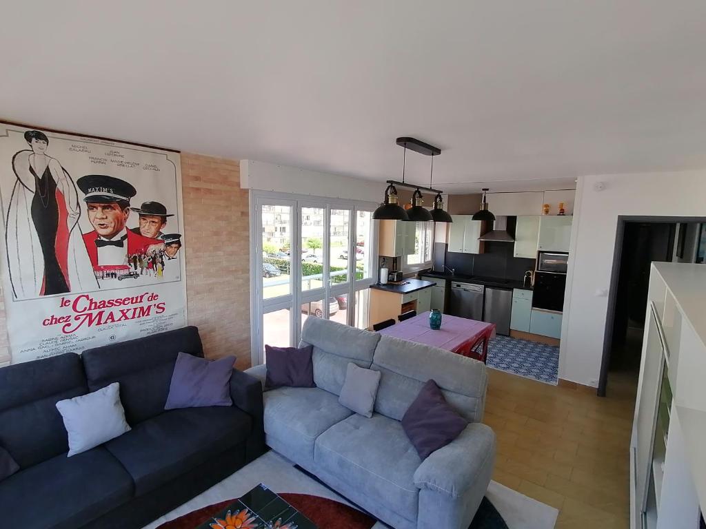 een woonkamer met een blauwe bank en een keuken bij appartement 50 m2 vue mer in Villers-sur-Mer