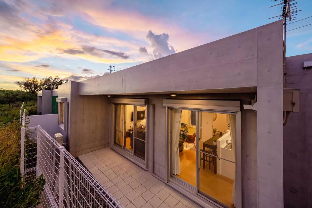a house with sliding glass doors on a balcony at Casa Medas Miyakojima in Hirara