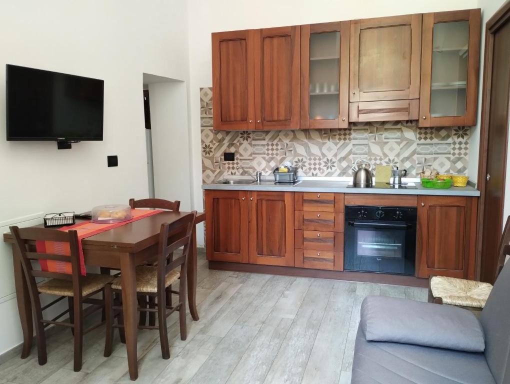 a kitchen with wooden cabinets and a table with chairs at Guest House La Casa del Mandatario in LʼAquila