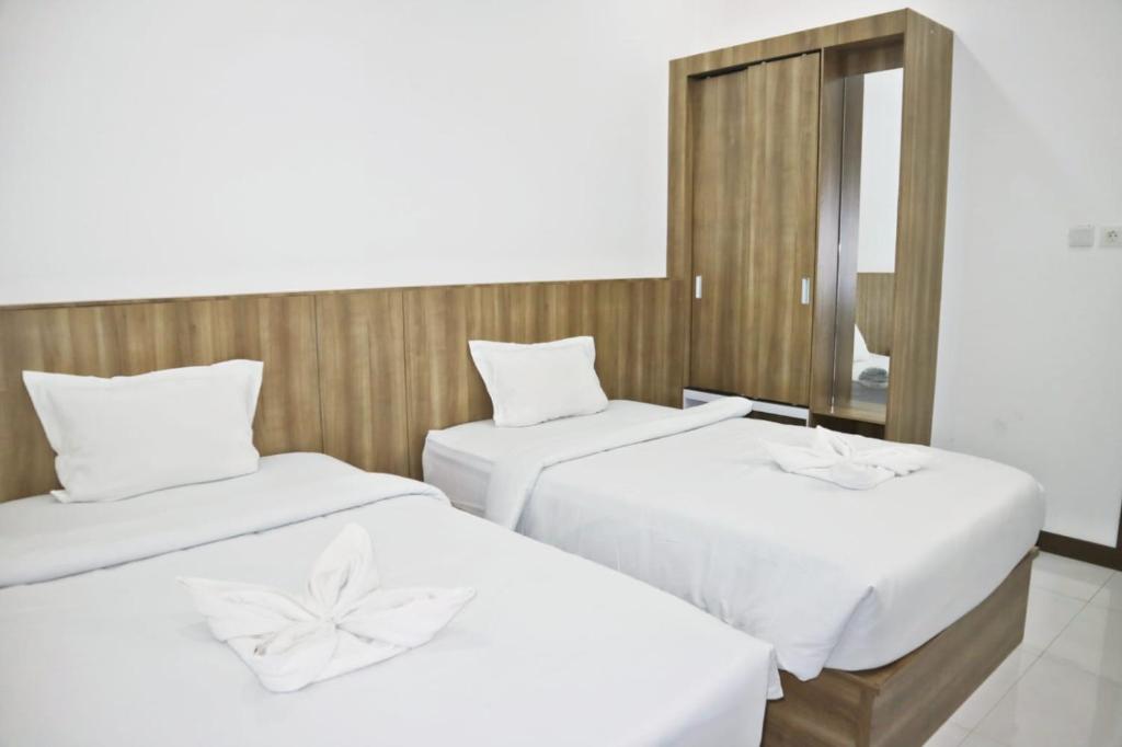 Hotel Bhakti في بادانج: سريرين في غرفة الفندق مع مرآة