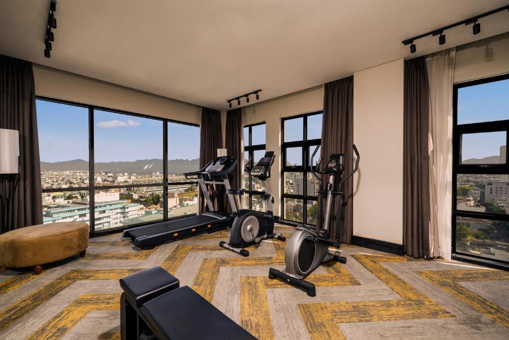 A glass-walled fitness room with cardio machines and city views.