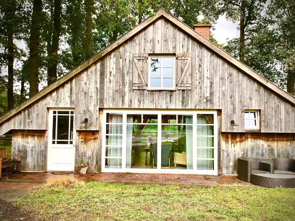 eine Holzscheune mit einer weißen Tür und Fenstern in der Unterkunft Ferienhaus auf dem Bauernhof in Bad Bentheim