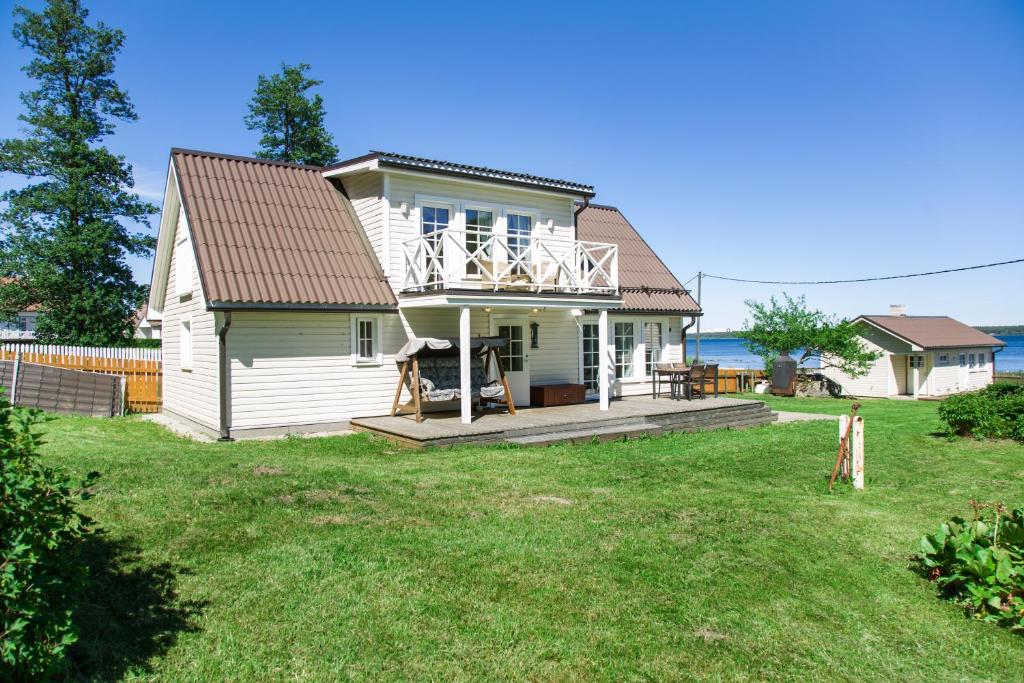 ein kleines weißes Haus mit einer Terrasse auf einem Hof in der Unterkunft Nordic Bliss beach house - Käsmu in Käsmu