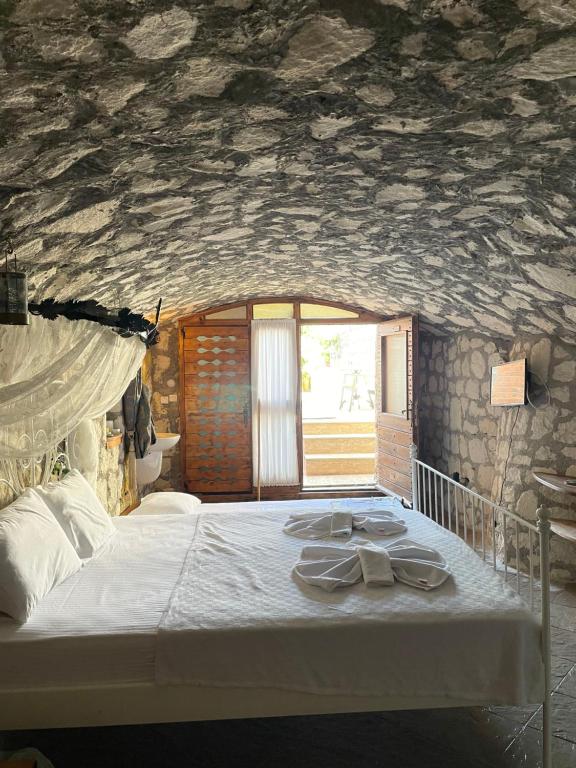 ein Schlafzimmer mit einem Bett mit einer Steinmauer in der Unterkunft Ata Boutique Hotel in Altınyunus