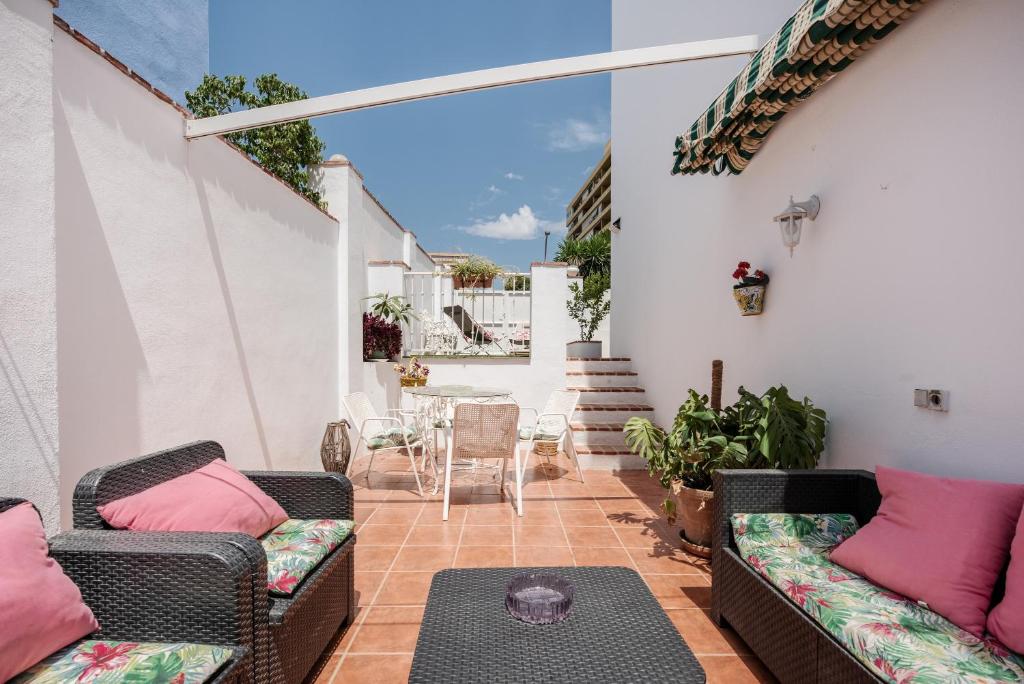 un patio con 2 sofás de mimbre y una mesa en Casa Beramendi, en Torremolinos