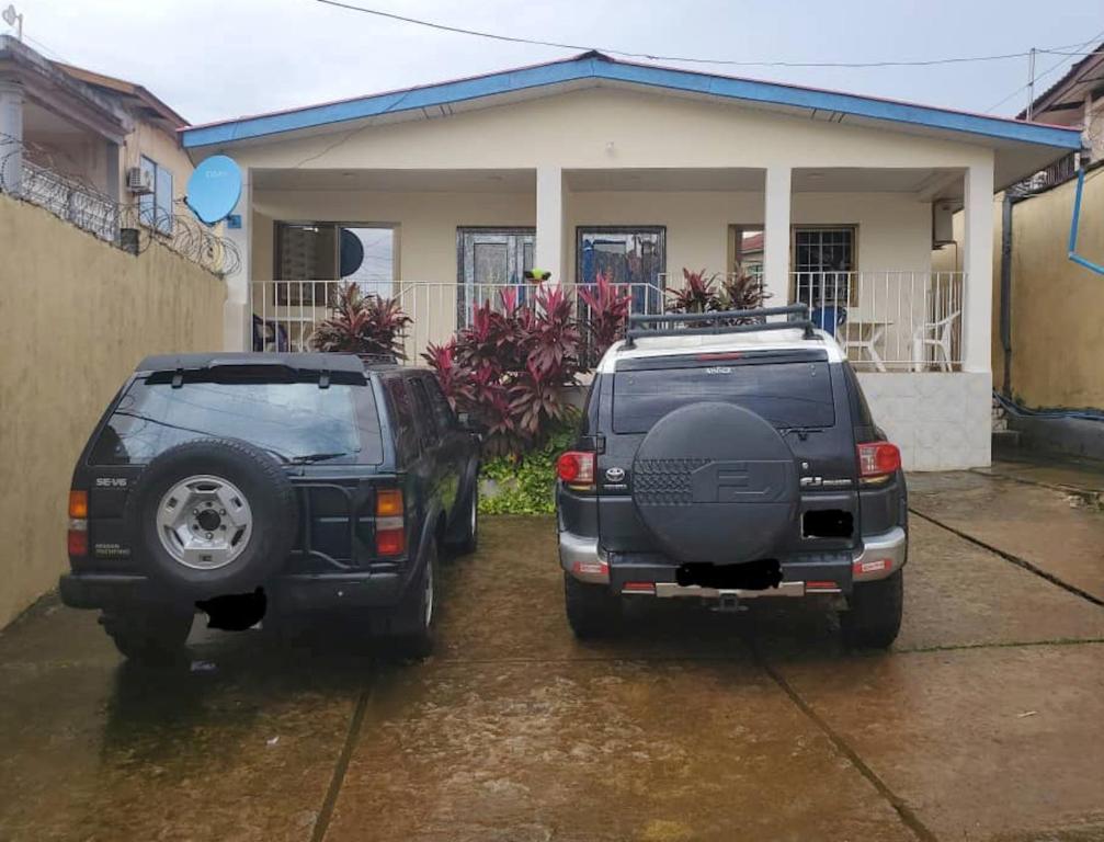 dois veículos estacionados em frente a uma casa em Savagem Furnished Apartment em Freetown