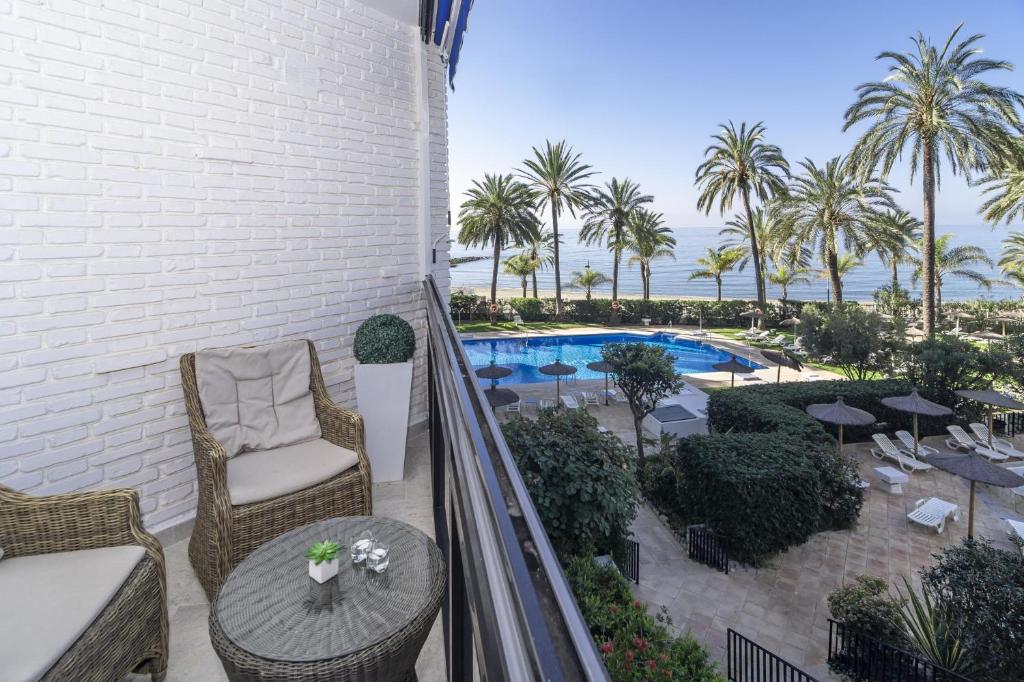 einen Balkon mit einem Tisch, Stühlen und einem Pool in der Unterkunft Sea promenade apartment in Marbella M27 in Marbella