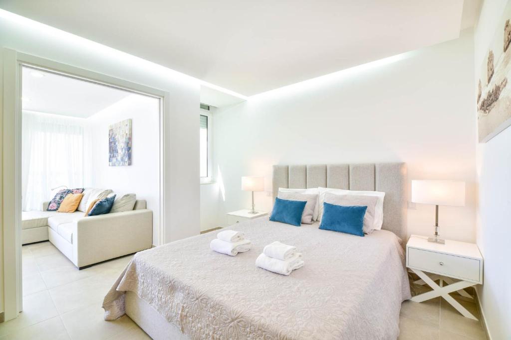 una camera da letto bianca con un letto e asciugamani di Casa Nico OceanView -Apartment 1901 a Portimão